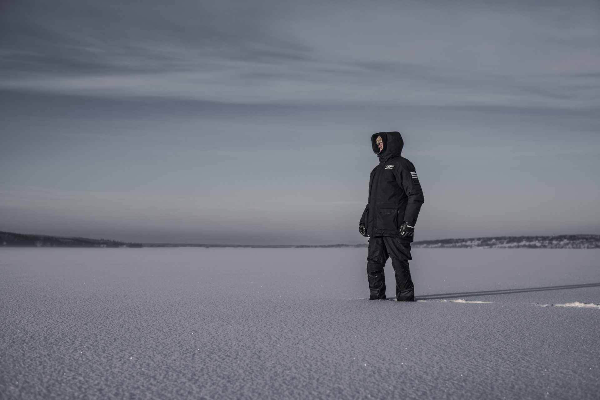 man standing in deep snow wearing black jacket from auk protection
